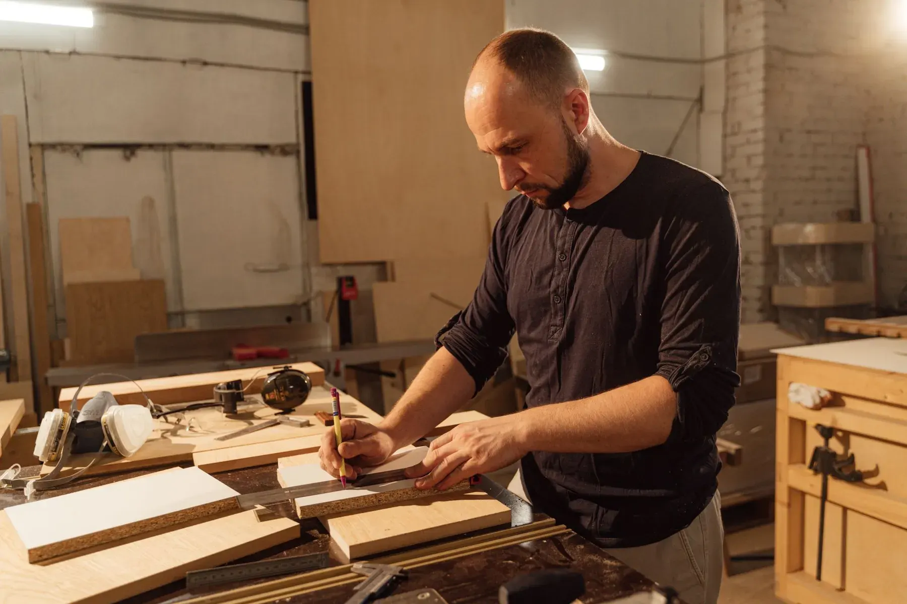 Cabinetmaker measuring wooden boards at a workbench in a Lehigh Acres workshop
